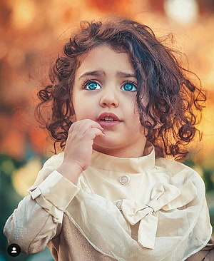 Portrait of a Toddler Girl with Curly Hair and Blue Eyes Wearing a Cream Bow Blouse HD phone wallpaper