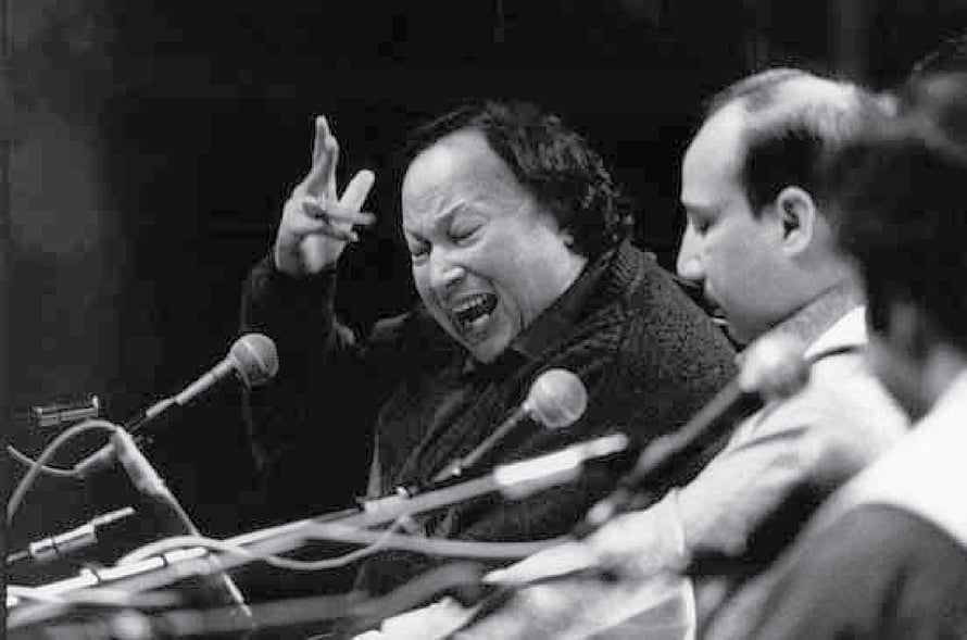 Nusrat Fateh Ali Khan performing passionately at a microphone with expressive hand gesture HD wallpaper