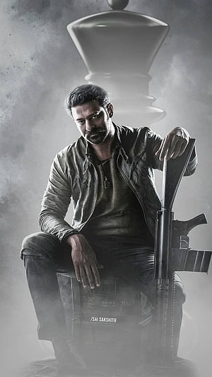 Prabhas as Raghavendra in gritty action pose with rifle and chess piece backdrop HD phone wallpaper