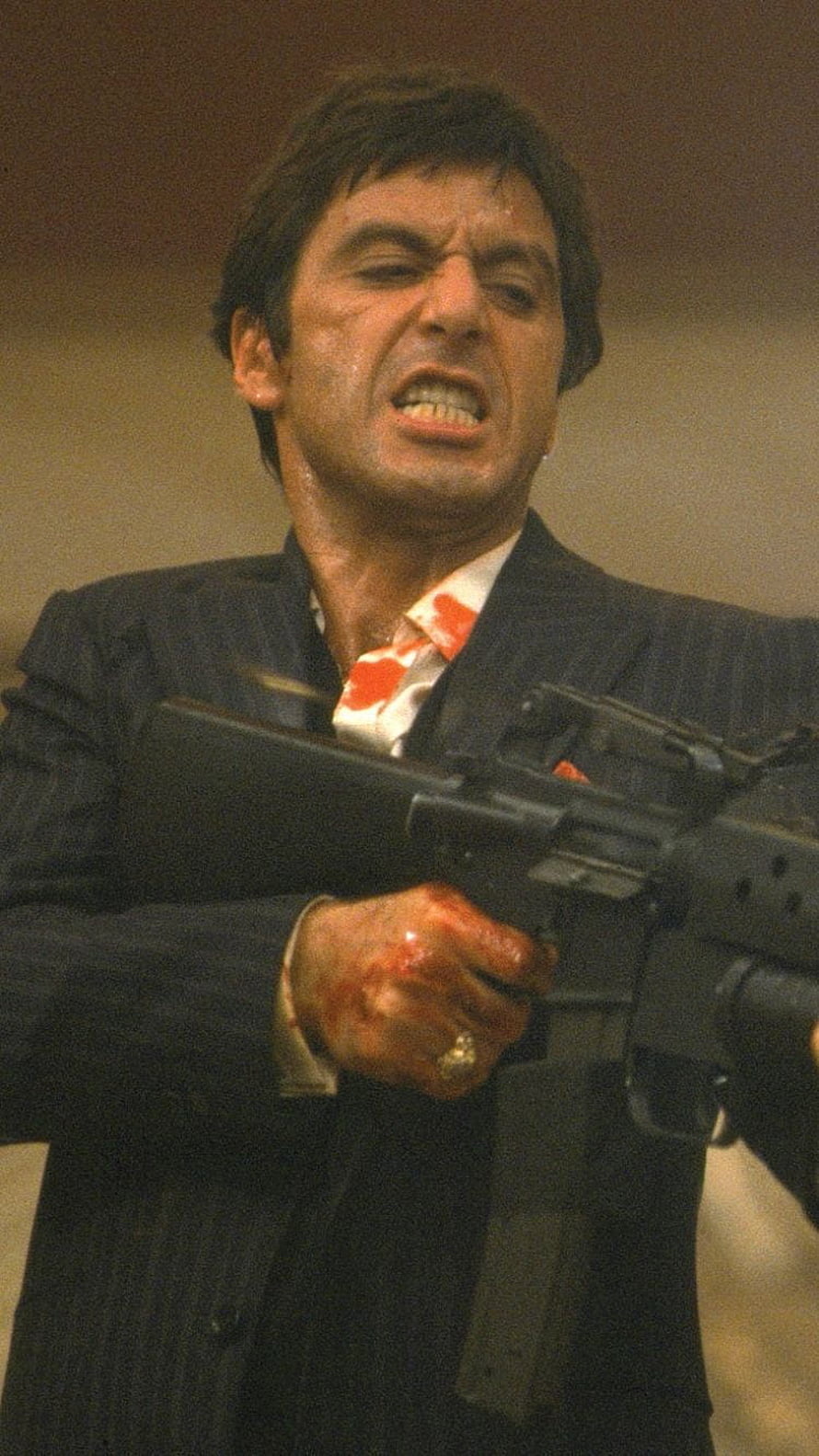 Al Pacino as Tony Montana in Scarface holding an assault rifle with a bloodied hand HD phone wallpaper