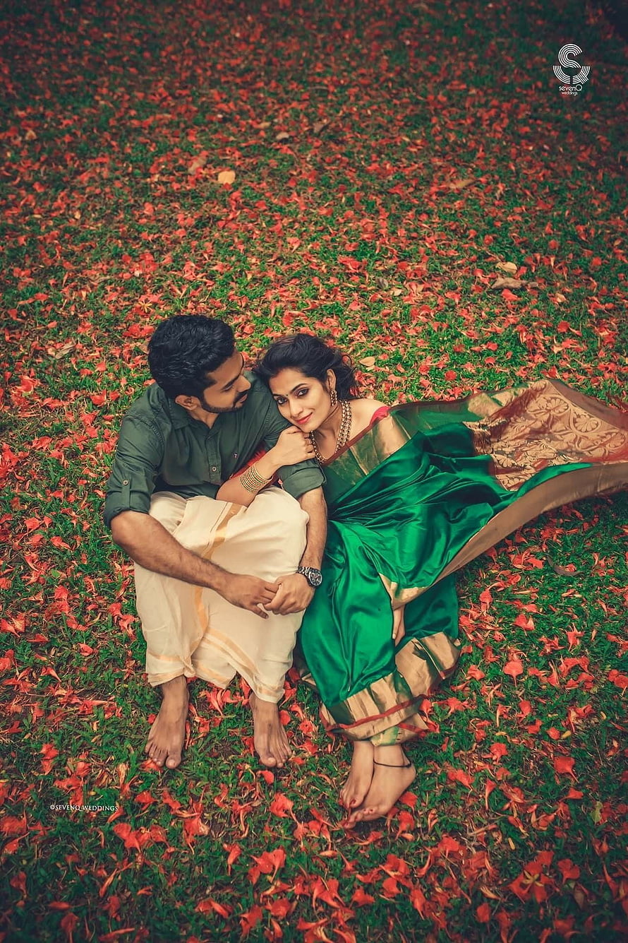 Kerala Wedding Couple in Traditional Attire Sitting on Flower-Strewn Grass HD phone wallpaper