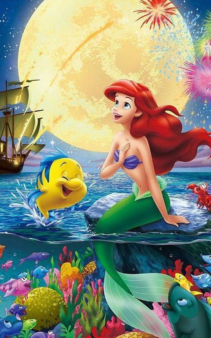 Ariel the Little Mermaid sitting on a rock with Flounder and fireworks under a full moon HD phone wallpaper