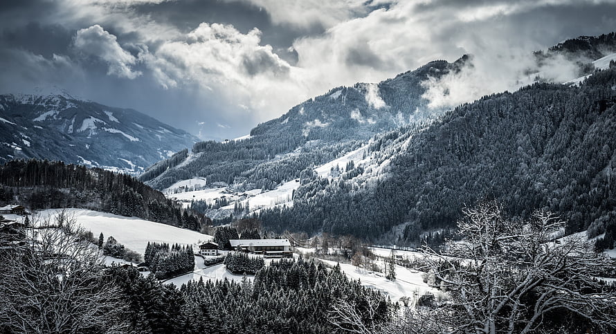 Snow-Covered Alpine Valley with Dramatic Clouds and Evergreen Forests HD wallpaper