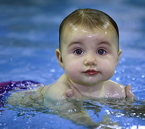 Adorable Baby Boy Floating in Blue Pool Water with Gentle Expression HD wallpaper