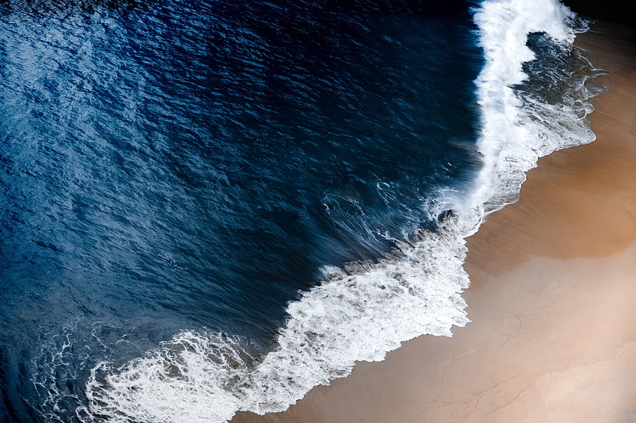 Aerial View of Bali Beach with Deep Blue Ocean Waves and White Foam on Sandy Shore HD wallpaper