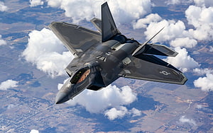 F-22 Raptor Stealth Fighter Jet Banking Through Clouds Over Rural Landscape HD wallpaper