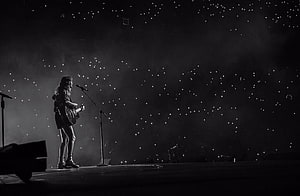 Taylor Swift performing solo with acoustic guitar on a dark concert stage under starry lights HD wallpaper