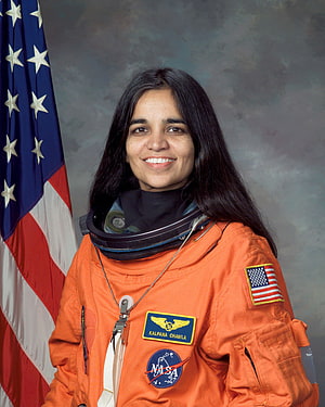 Kalpana Chawla in NASA orange flight suit with American flag backdrop HD phone wallpaper
