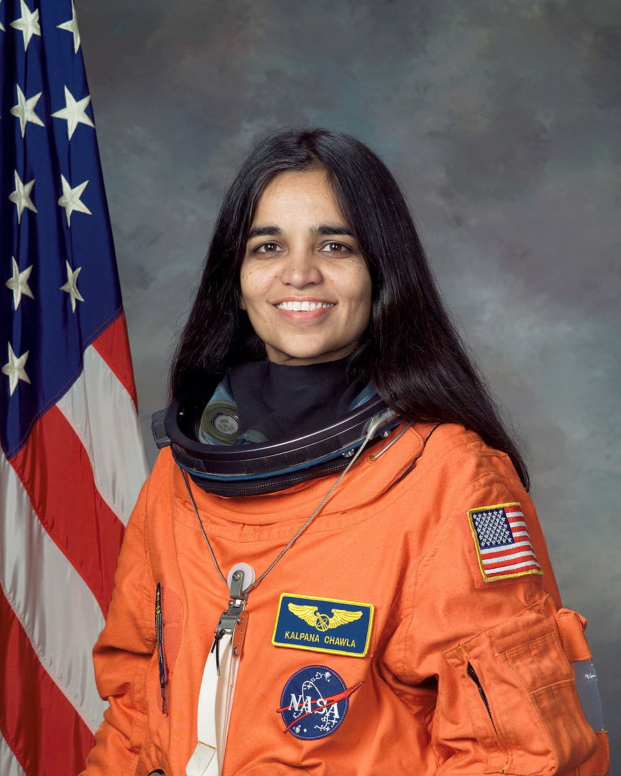 Kalpana Chawla in NASA orange flight suit with American flag backdrop HD phone wallpaper