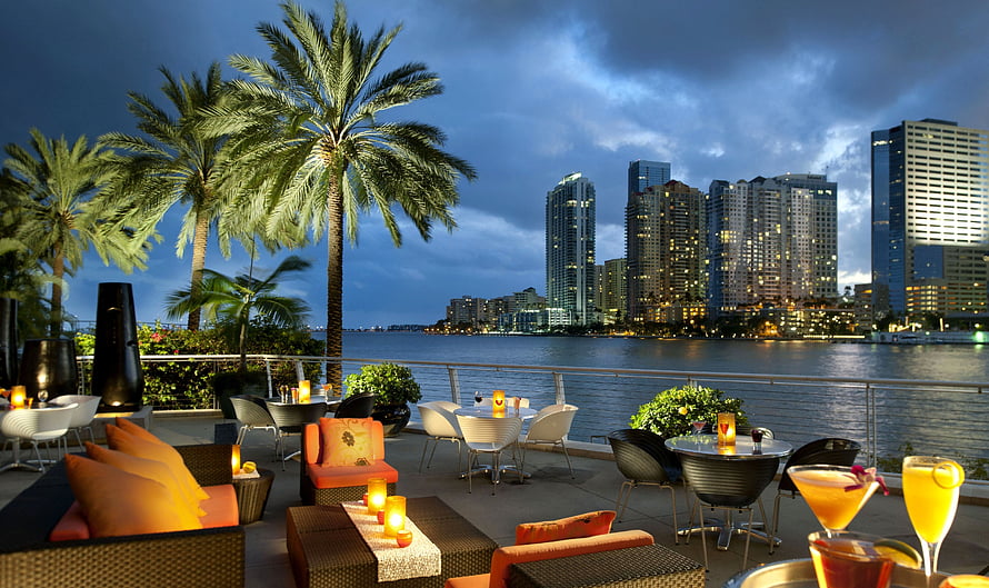 Miami waterfront rooftop lounge at dusk with palm trees and city skyline HD wallpaper