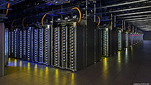Rows of illuminated server racks in a modern data center with blue and yellow lighting HD wallpaper