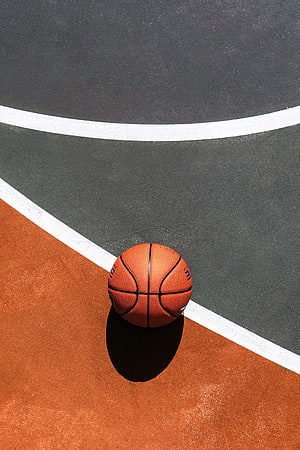 Orange basketball resting on a painted court with bold white boundary lines and contrasting surfaces HD phone wallpaper
