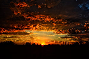 Dramatic Orange Sunset Sky with Dark Clouds Over Silhouetted Horizon HD wallpaper