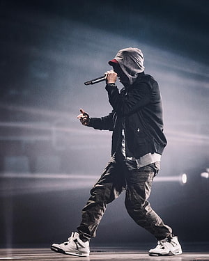 Eminem performing on stage in a grey hoodie and black jacket during a live concert HD phone wallpaper