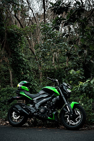 Bajaj Dominar 400 Motorcycle in Green and Black Parked in a Lush Forest Setting HD phone wallpaper