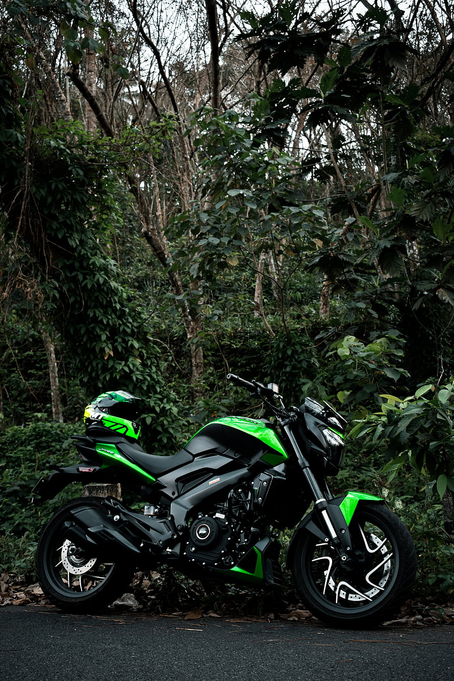 Bajaj Dominar 400 Motorcycle in Green and Black Parked in a Lush Forest Setting HD phone wallpaper