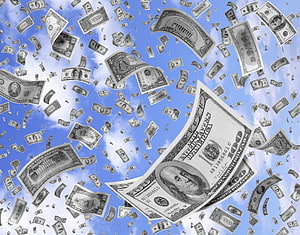 US Dollar Bills Falling Against a Bright Blue Sky with White Clouds HD wallpaper