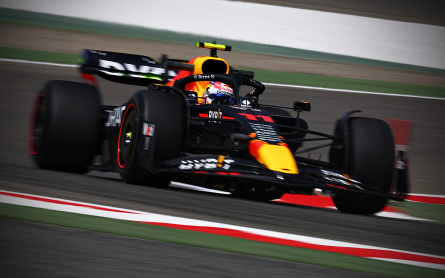 Sergio Perez in the Red Bull Racing RB18 Formula 1 car speeding on a race track HD wallpaper