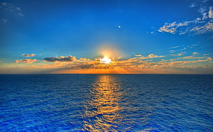 Golden Sunset Over Calm Blue Ocean With Scattered Clouds And Sunlight Reflection HD wallpaper