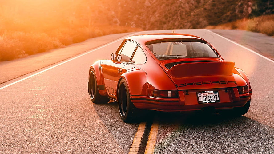 Classic Red Porsche 911 Driving on a Winding Road at Golden Hour HD wallpaper