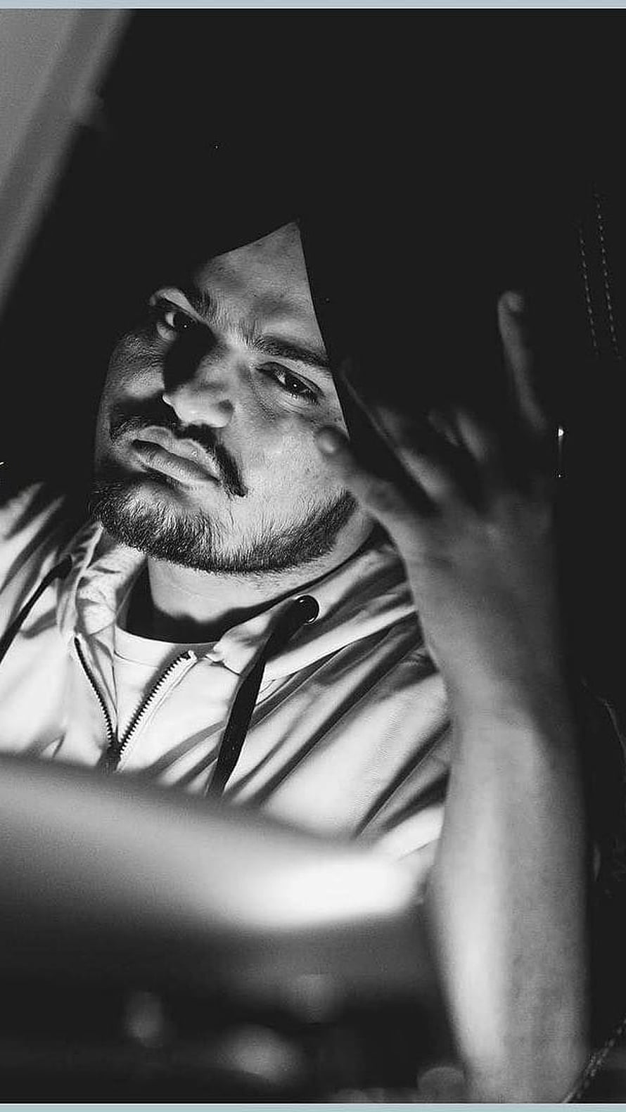 Black and white portrait of a man in a hoodie looking through a window with hand raised, Sidhu Moose Wala Black, Punjabi, Actor, Singer HD phone wallpaper