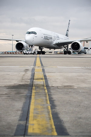 Airbus A350 XWB wide-body jet on airport taxiway with tow vehicle and overcast sky HD phone wallpaper