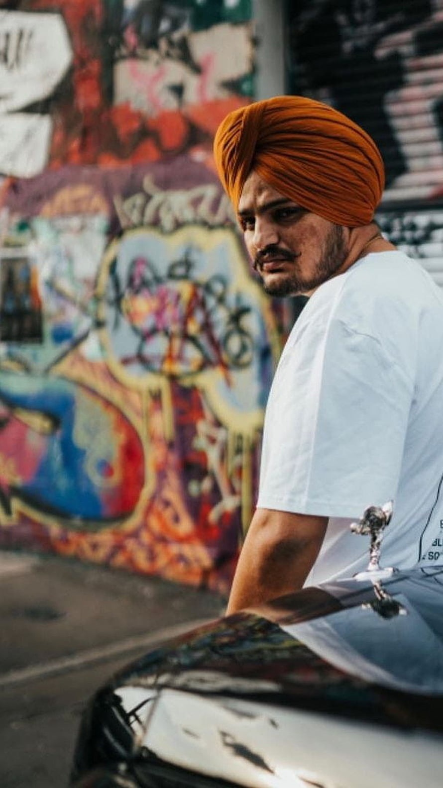 Portrait of a man wearing an orange turban leaning against a car with graffiti background, Sidhu Moose Wala, punjabi HD phone wallpaper