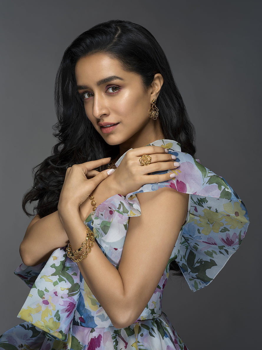 Shraddha Kapoor in a floral ruffled dress with gold jewelry against a grey studio backdrop HD phone wallpaper