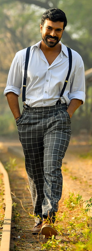 Ram Charan in white shirt and checkered trousers with suspenders on a railway track HD phone wallpaper