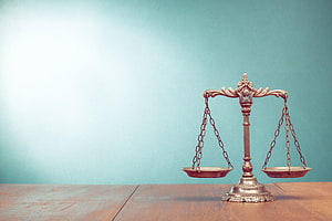 Vintage brass balance scale on a wooden table against a soft teal background HD wallpaper