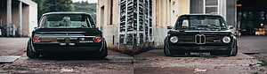 Classic Black BMW 2002t Stance Build Front and Rear View in Industrial Setting HD wallpaper
