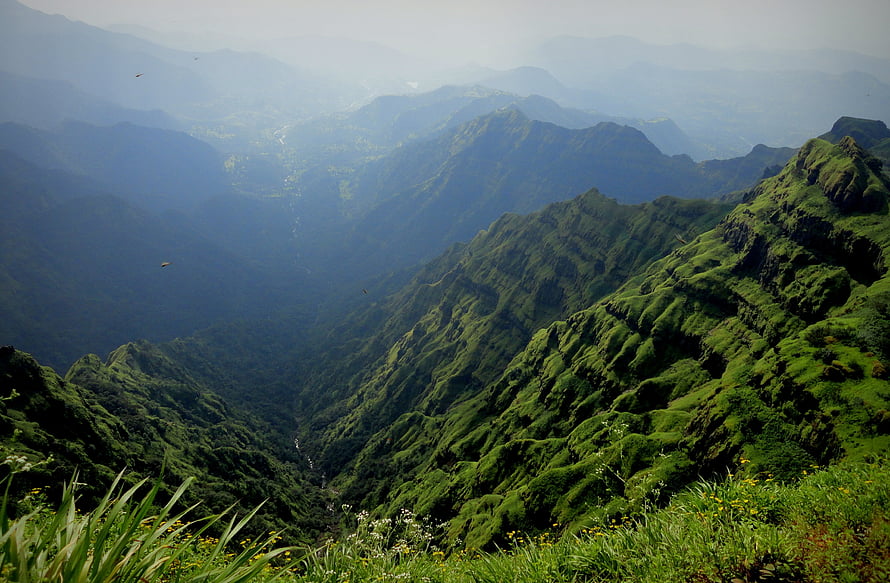 Misty Green Mountain Ranges with Deep Valleys and Lush Vegetation HD wallpaper