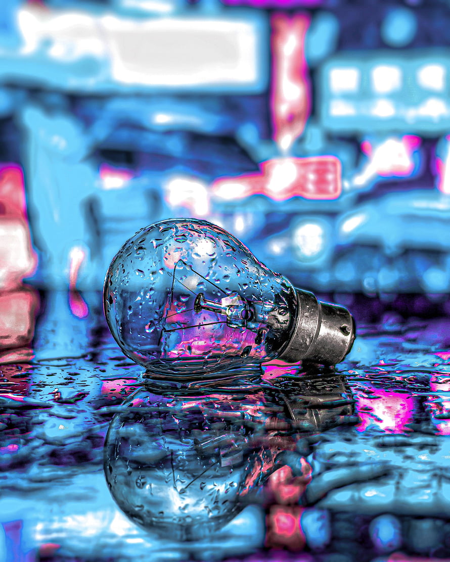 Neon-lit incandescent light bulb with water droplets on a reflective wet surface HD phone wallpaper