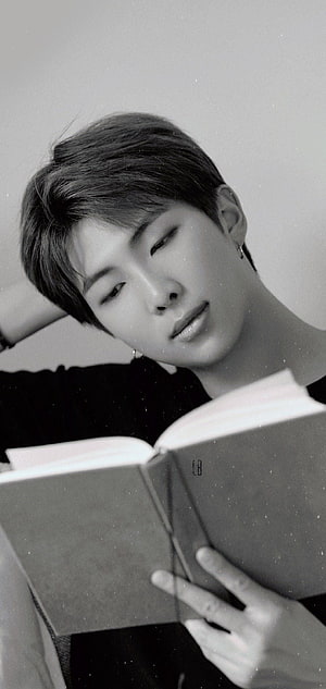RM from BTS in a moody black and white portrait reading a book HD phone wallpaper