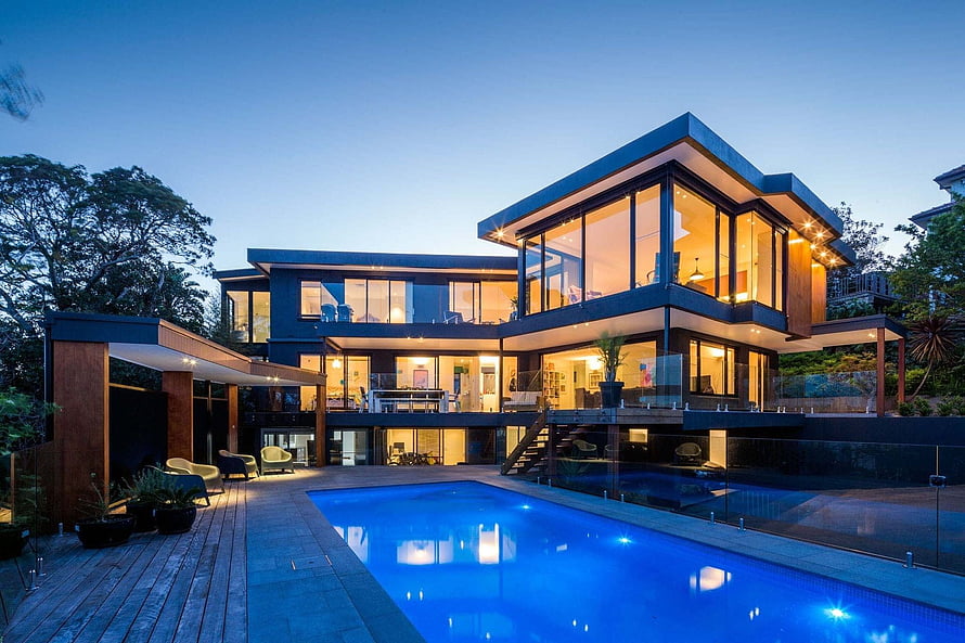 Modern Luxury Villa with Infinity Pool at Dusk Featuring Floor-to-Ceiling Glass Windows and Warm Interior Lighting HD wallpaper