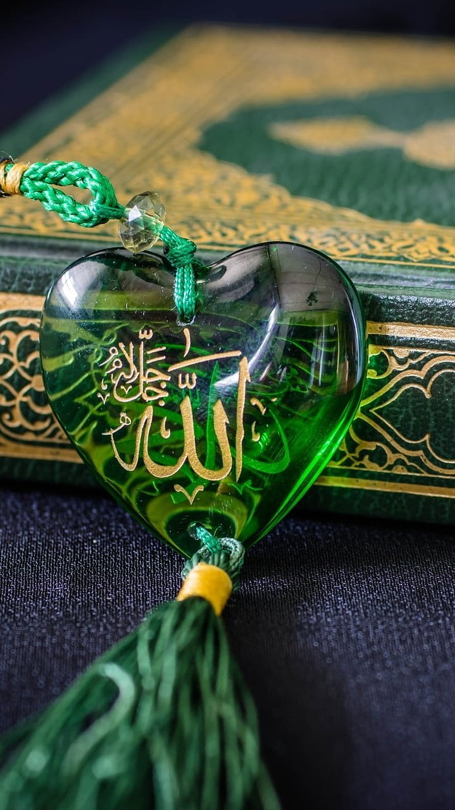 Green Heart-Shaped Amulet with Arabic Calligraphy and Tassel on Quran HD phone wallpaper