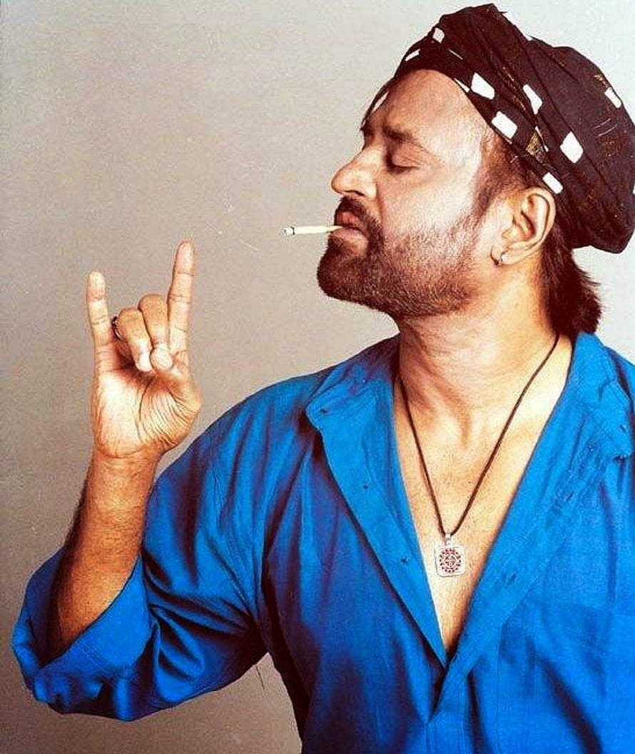 Actor Saif Ali Khan in a blue shirt with a bandana smoking a cigarette and making a hand gesture HD phone wallpaper