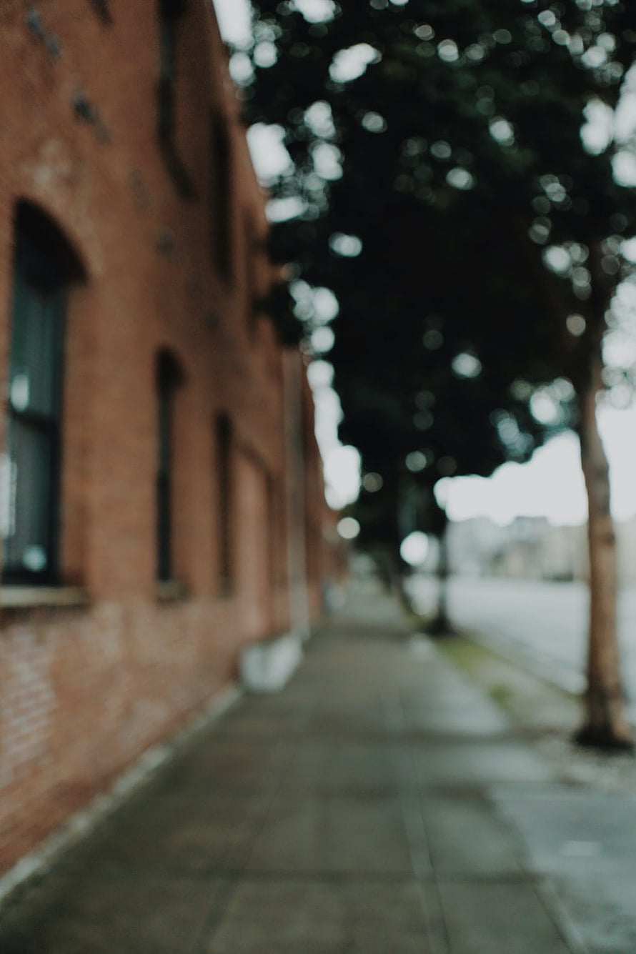 Blurred Urban Street Scene With Red Brick Building And Trees HD phone wallpaper
