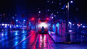Neon-lit rainy city street with a lone figure standing on tram tracks at night HD wallpaper