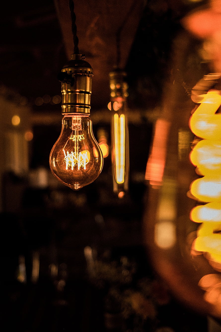 Vintage Edison Bulb Hanging in Warm Dimly Lit Interior with Bokeh Background HD phone wallpaper