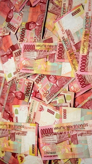 Scattered pile of Indonesian 100,000 Rupiah banknotes with red and orange color scheme HD phone wallpaper