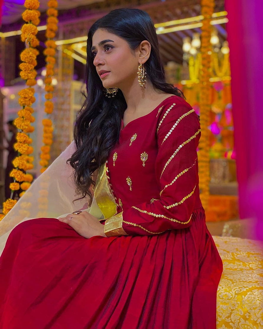 Sehar Khan in a deep red embroidered Pakistani dress with gold detailing and marigold backdrop HD phone wallpaper