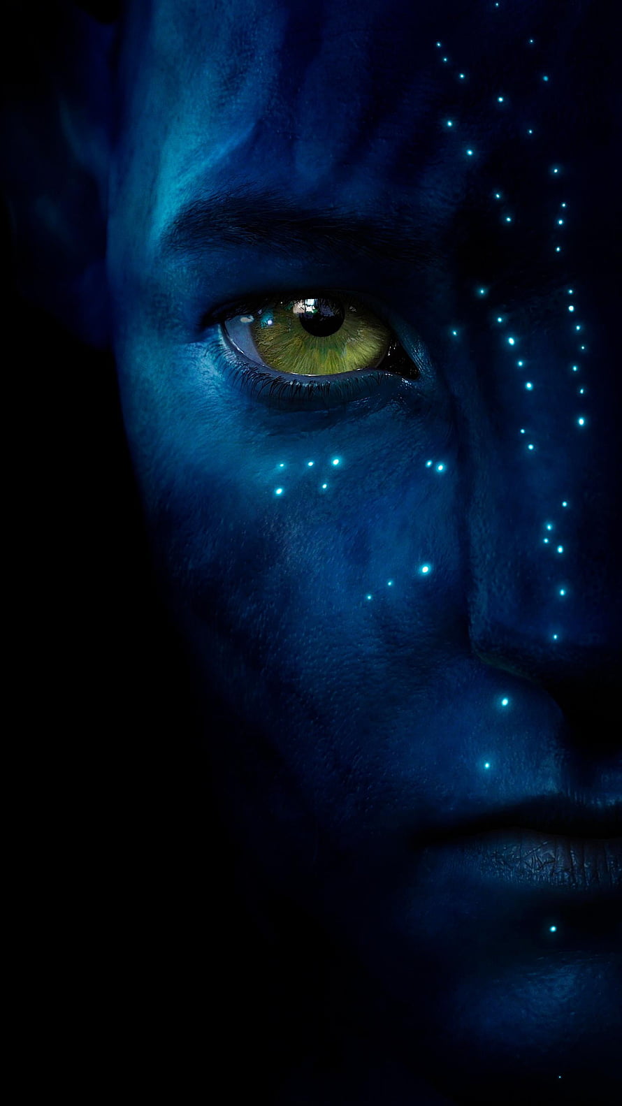 Close-up of a blue-skinned Na'vi face with glowing bioluminescent dots and a striking green eye from the Avatar film HD phone wallpaper