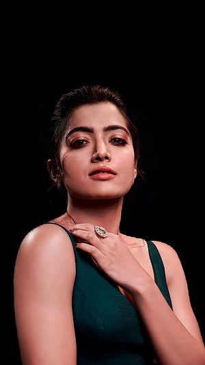 Rashmika Mandanna in a dark green dress with a statement ring against a black background HD phone wallpaper