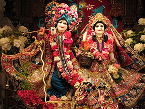 Radha Krishna idols adorned in vibrant floral garlands and intricate traditional attire HD wallpaper