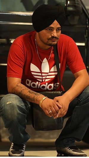 Diljit Dosanjh wearing a red Adidas t-shirt and black turban sitting with a bag HD phone wallpaper