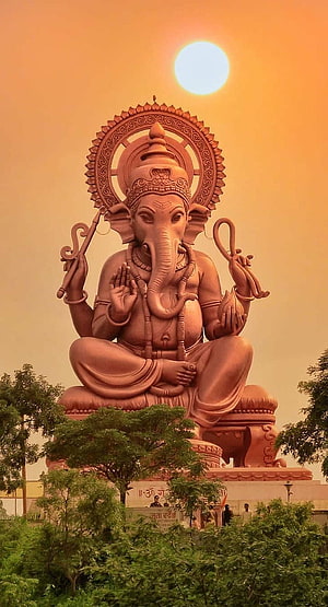Majestic Lord Ganesha Statue Silhouetted Against a Golden Sunset Sky HD phone wallpaper