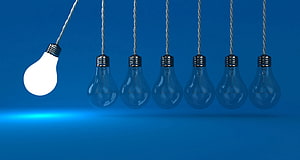 Illuminated Light Bulb Standing Out Among Unlit Bulbs on Blue Background HD wallpaper