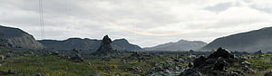Death Stranding Vast Rocky Landscape with Faint Rainbow Arc and Distant Mountain Peaks HD wallpaper