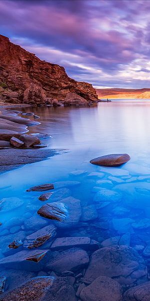Serene Blue Lagoon with Smooth Rocks and Purple Sunset Sky HD phone wallpaper